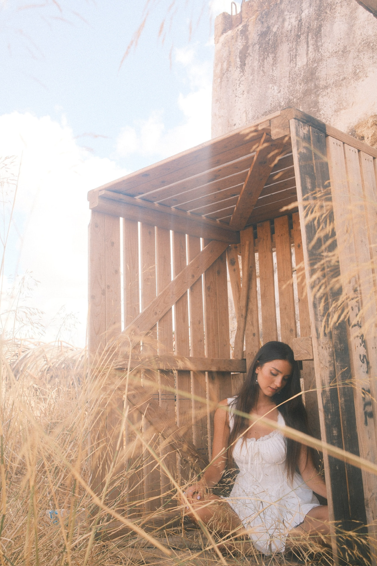 Emily Lilian seated by a wooden structure in golden sunlight
